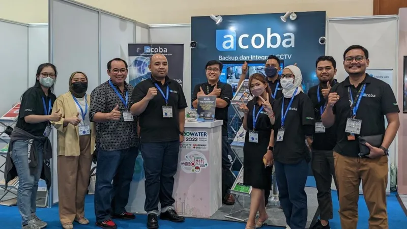 Tim Acoba berfoto bersama di depan booth pameran dengan spanduk Backup dan Integrasi CCTV